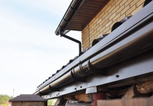 Holder gutter drainage system on the roof. Closeup of problem areas for plastic rain gutter waterproofing.